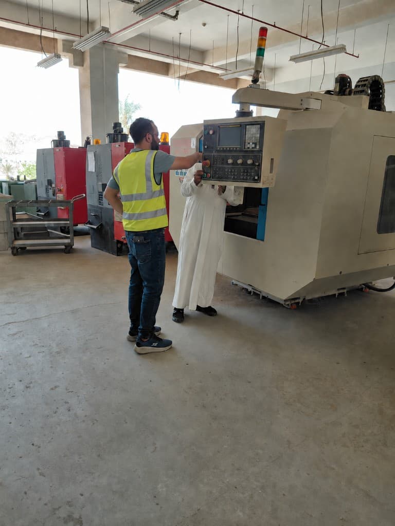 Technician and client reviewing a CNC machine control panel during commissioning