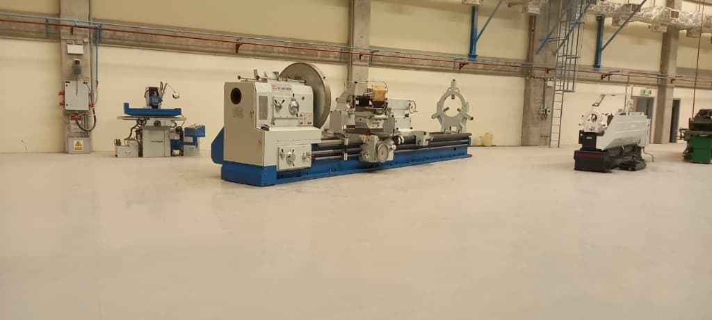Engine lathe and supporting machines on a clean industrial workshop floor