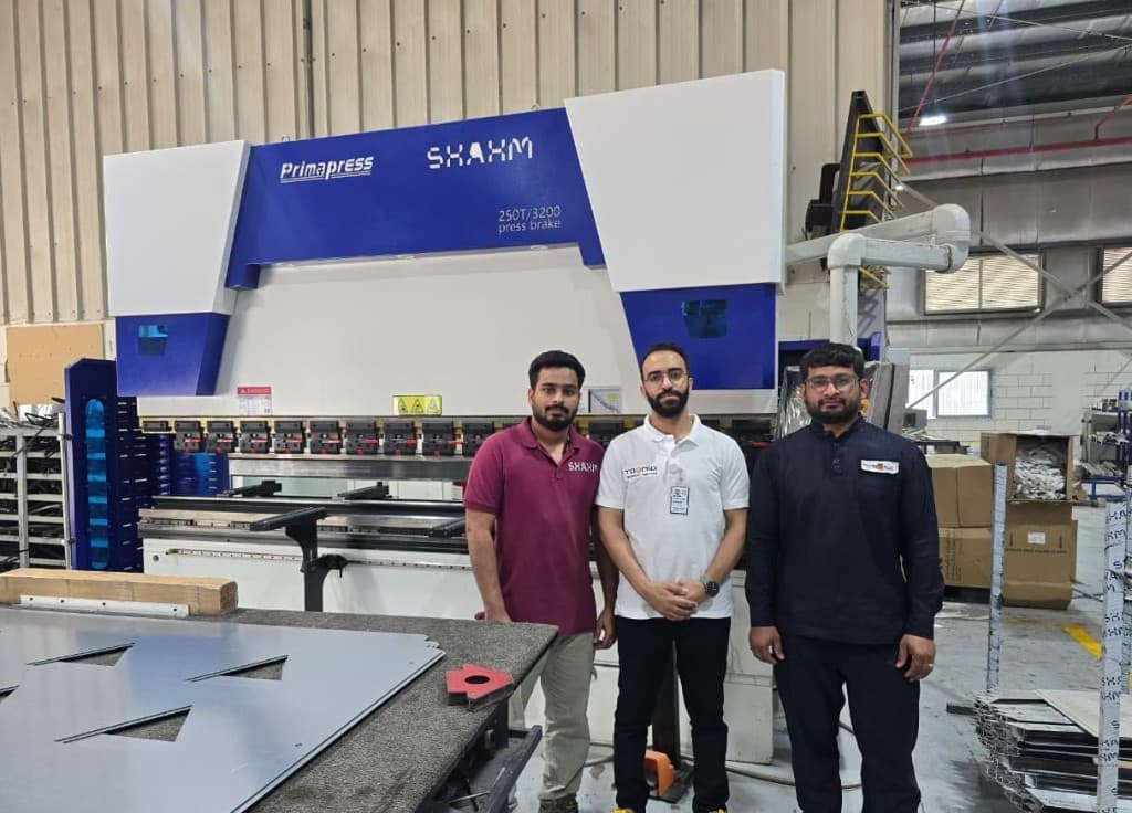 Team standing with a 250T press brake after installation on the factory floor