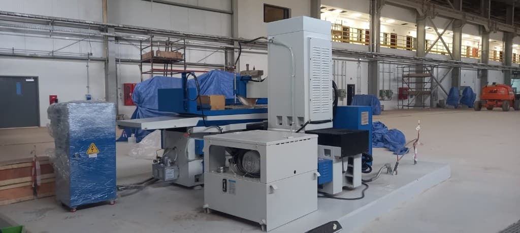 Surface grinder and control cabinet during installation in an industrial hall